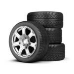 car tires, with one tire mounted on a wheel rim and a stack of three other tires.